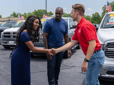 Car-Mart Associate greeting and shaking hands with a female customer outside on the lot.